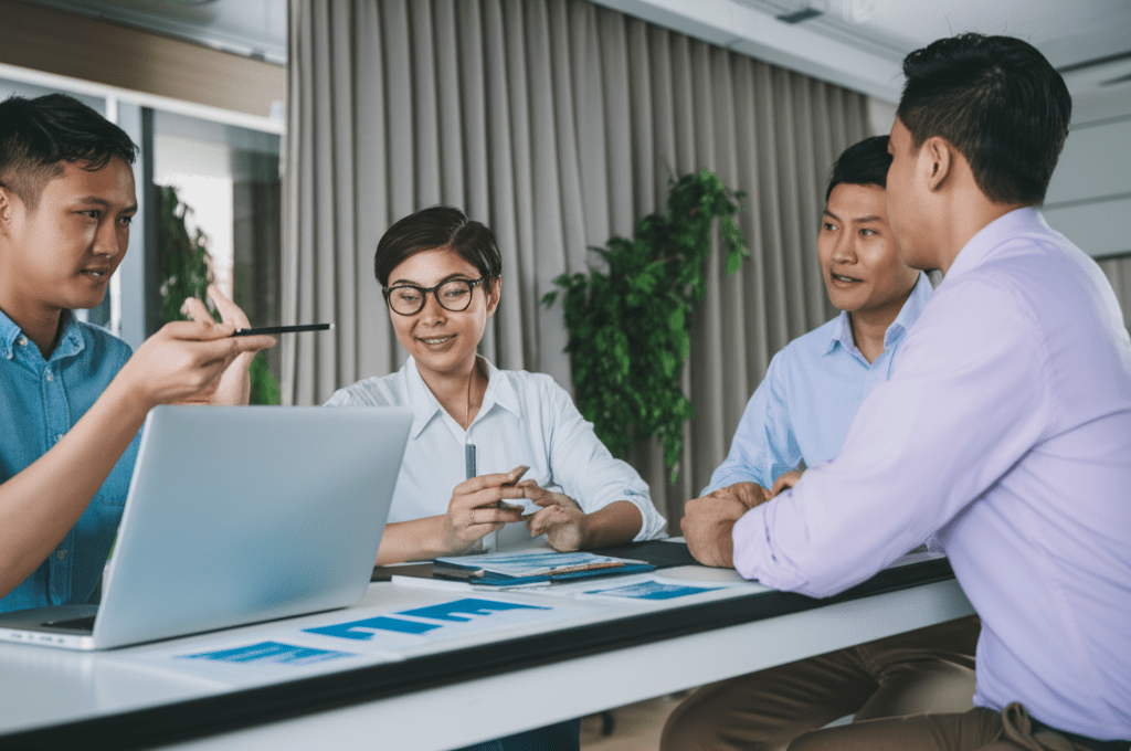 A professional business setting showing a diverse group of startup founders and a fractional CTO in a modern office discussing equity compensation models, with charts and laptops visible, symbolizing technology leadership, negotiation, and collaboration.