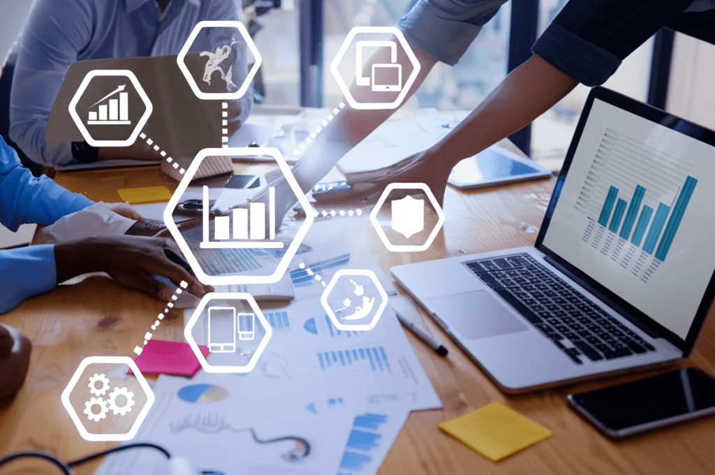 A diverse group of professionals collaborating around a table with laptops and digital devices, representing technology leadership and strategic planning in a modern business environment.